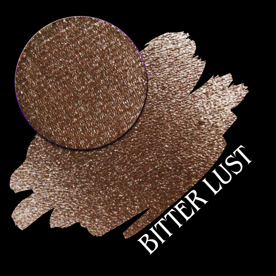 A round eyeshadow pan labeled 'BITTER LUST' made by Devinah Cosmetics, placed over a large crescent moon swatch of the same shimmering shifty eyeshadow on skin. The eyeshadow has shimmer sparkle colors brown, tan, beige, neutral.