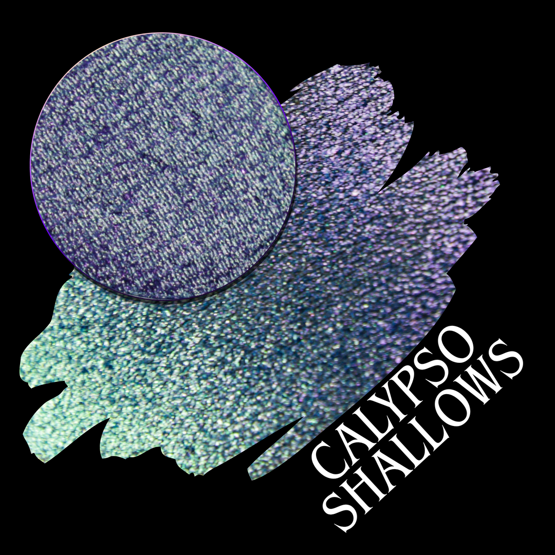 A round eyeshadow pan labeled 'CALYPSO SHALLOWS' made by Devinah Cosmetics, placed over a large crescent moon swatch of the same shimmering shifty eyeshadow on skin. The eyeshadow has a shift between colors gree, purple, blue.