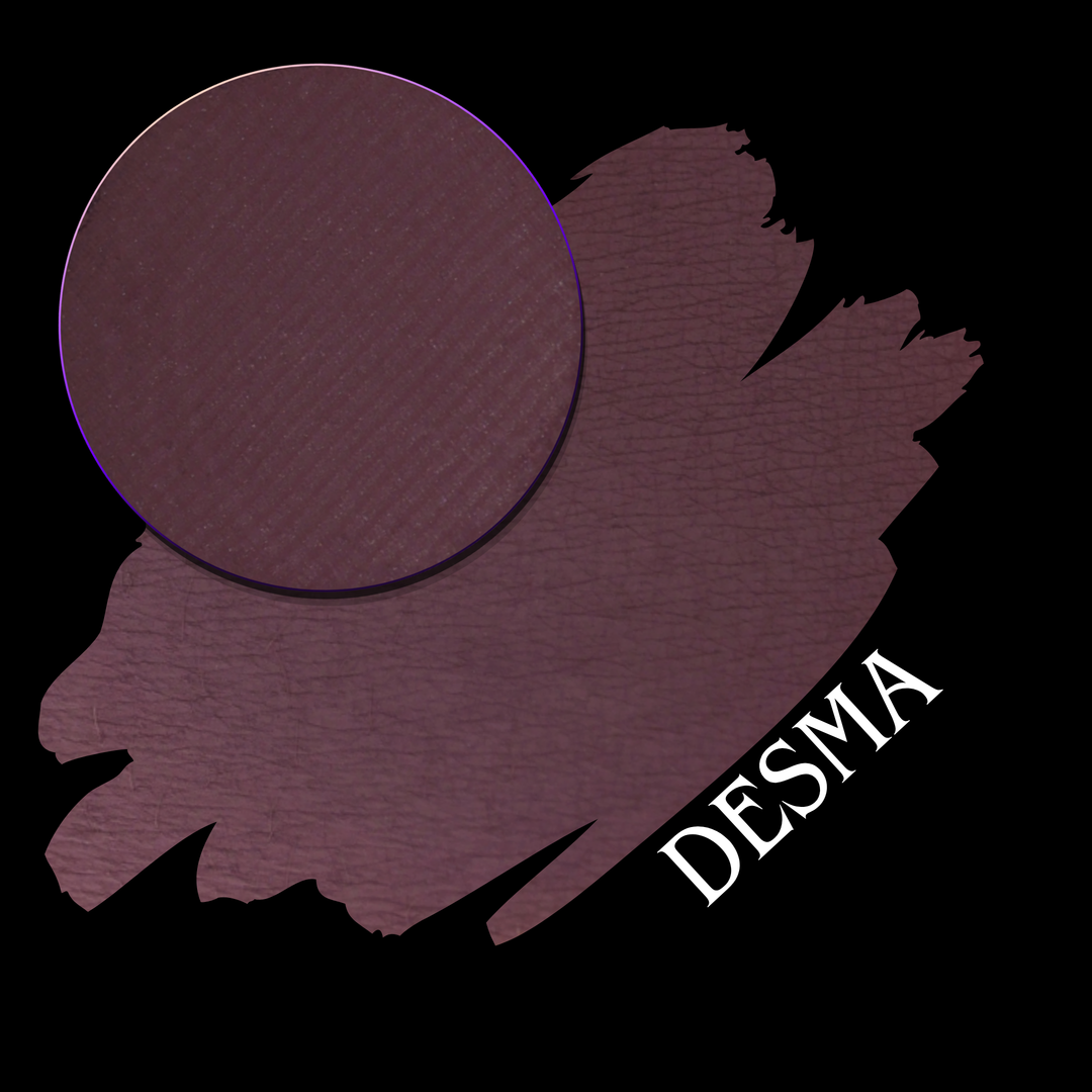 A makeup swatch showing a deep plum-purple color, with a circular makeup eyeshadow pan on a black background. The text 'DESMA' is written in white at the bottom right.