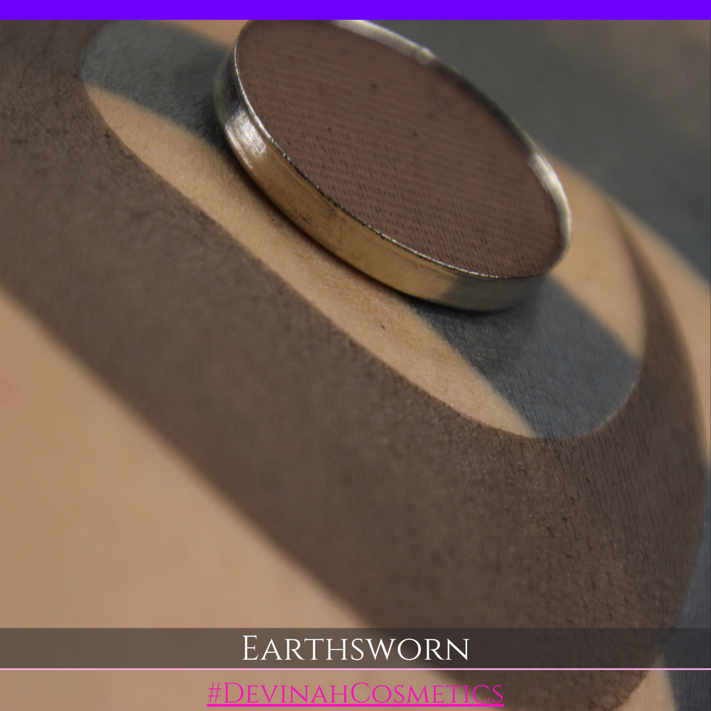 A makeup swatch showing a brown eyeshadow with a circular eyeshadow makeup pan, labeled 'EARTHSWORN' on a black background.