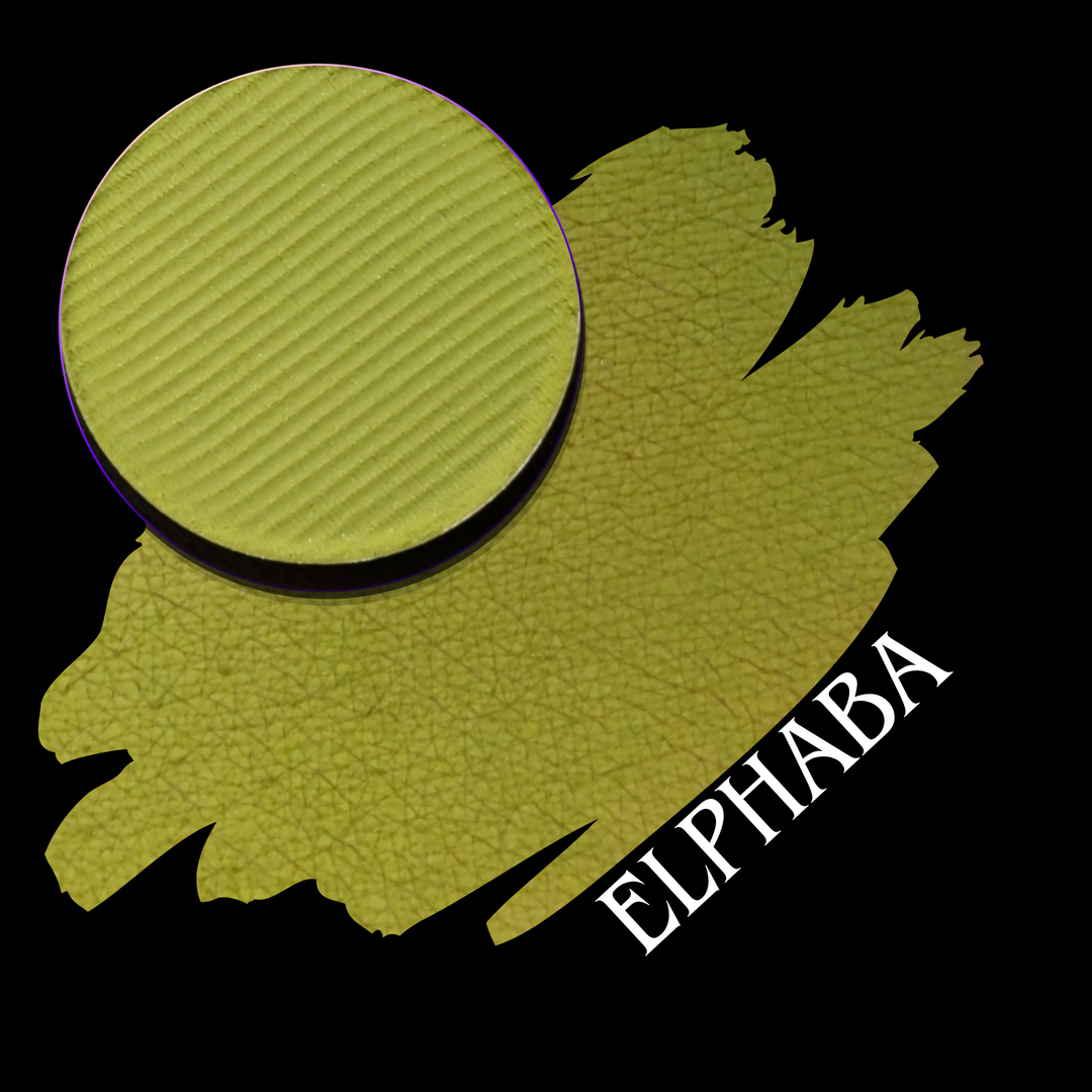 A textured circular makeup eyeshadow pan in a yellow-green shade labeled 'ELPHABA' is shown over a matching paint-like swatch on a black background.