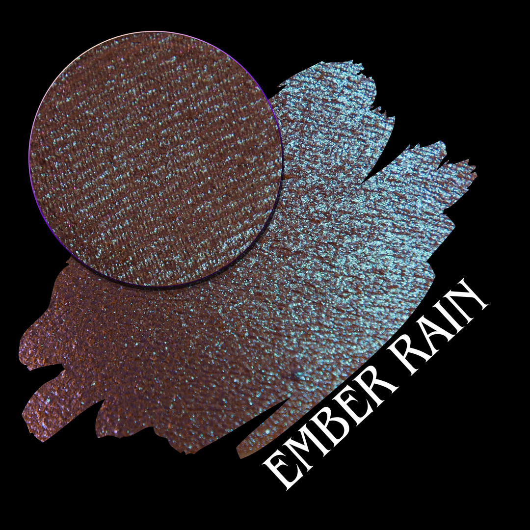 An eyeshadow swatch showing the shade 'Ember Rain' made by Devinah Cosmetics with a circular texture close-up on a black background.