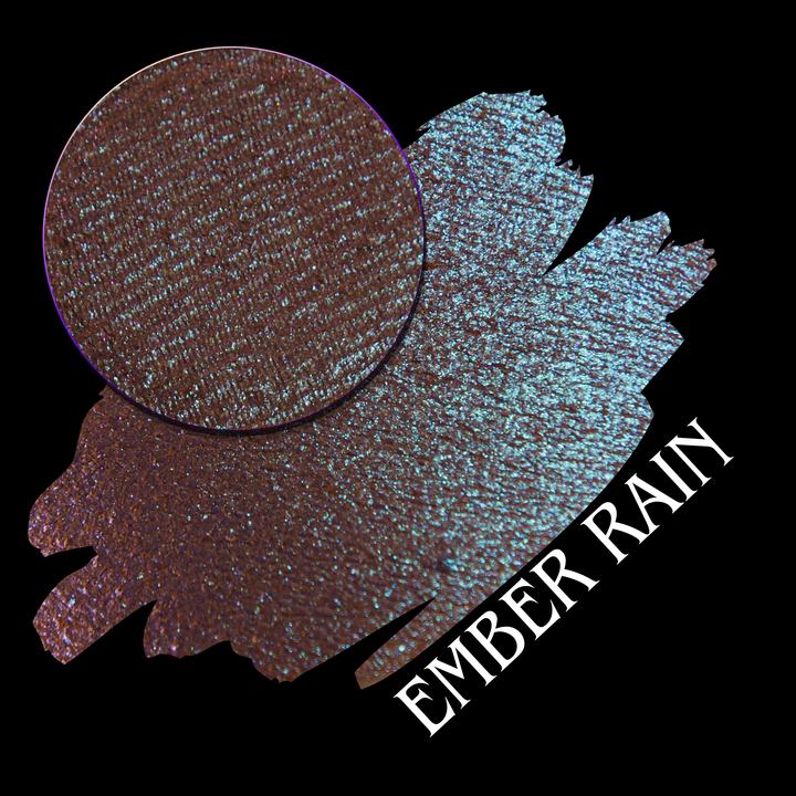 An eyeshadow swatch showing the shade 'Ember Rain' made by Devinah Cosmetics with a circular texture close-up on a black background.