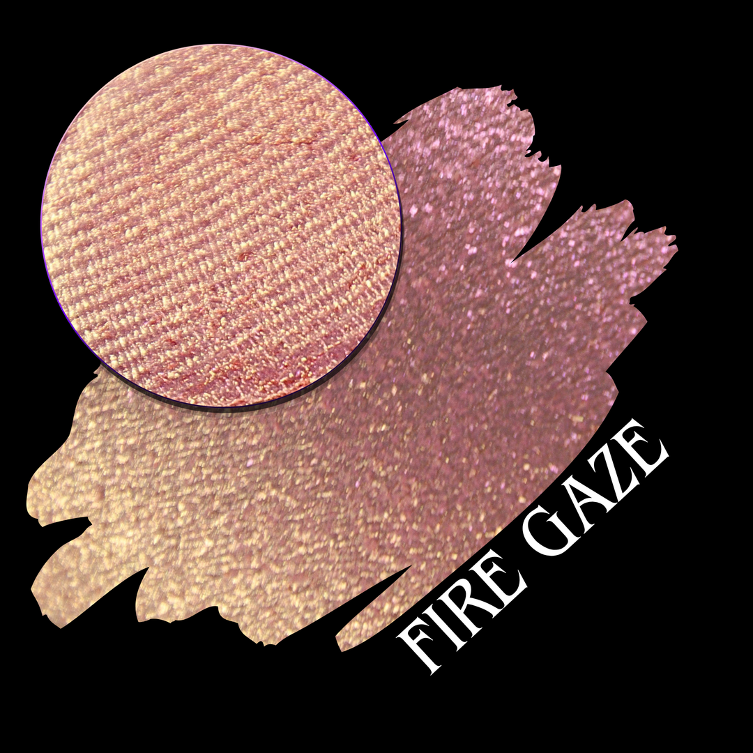 A makeup color swatch showing a shimmering pink-rose eyeshadow with a circular eyeshadow pan and the text 'FIRE GAZE' on a black background made by Devinah Cosmetics.