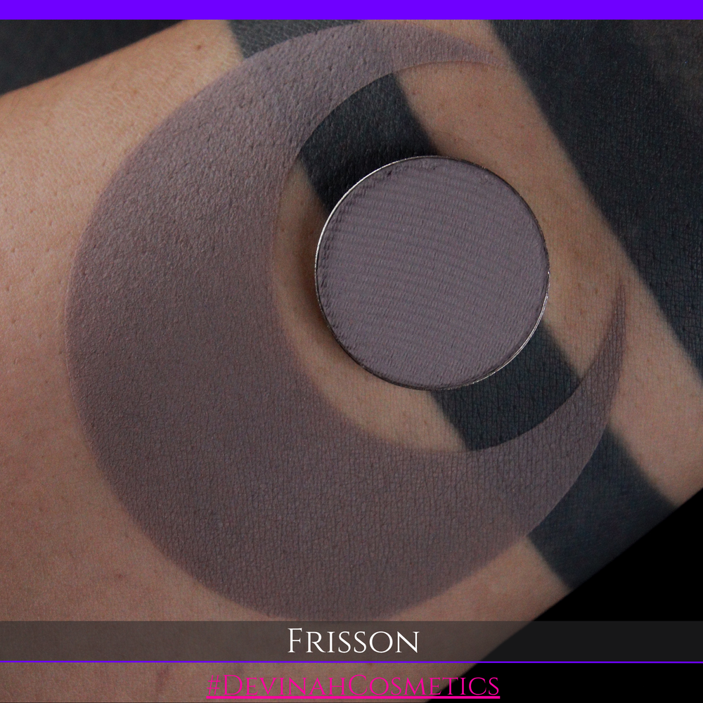 A close-up of a person's skin with a large circular swatch of mauve-gray eyeshadow and a smaller round pan of the same shade. The text 'FRISSON' and 'EYE SHADOWS' appears at the bottom.