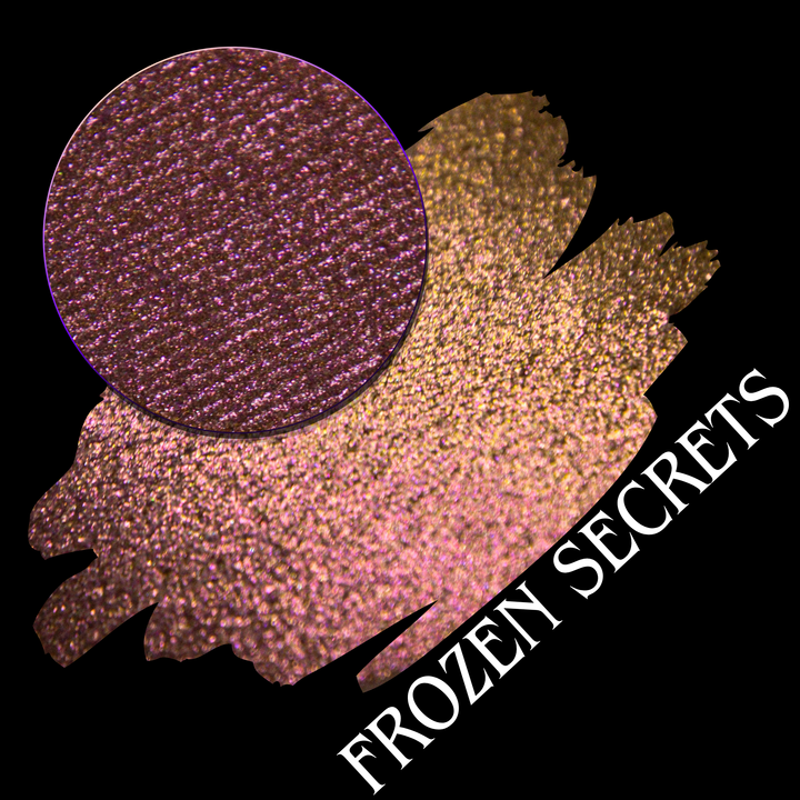 A cosmetic swatch showing a shimmering red pink-to-gold eyeshadow with a circular eyeshadow pan on a black background. White text reads 'FROZEN SECRETS' made by Devinah Cosmetics.