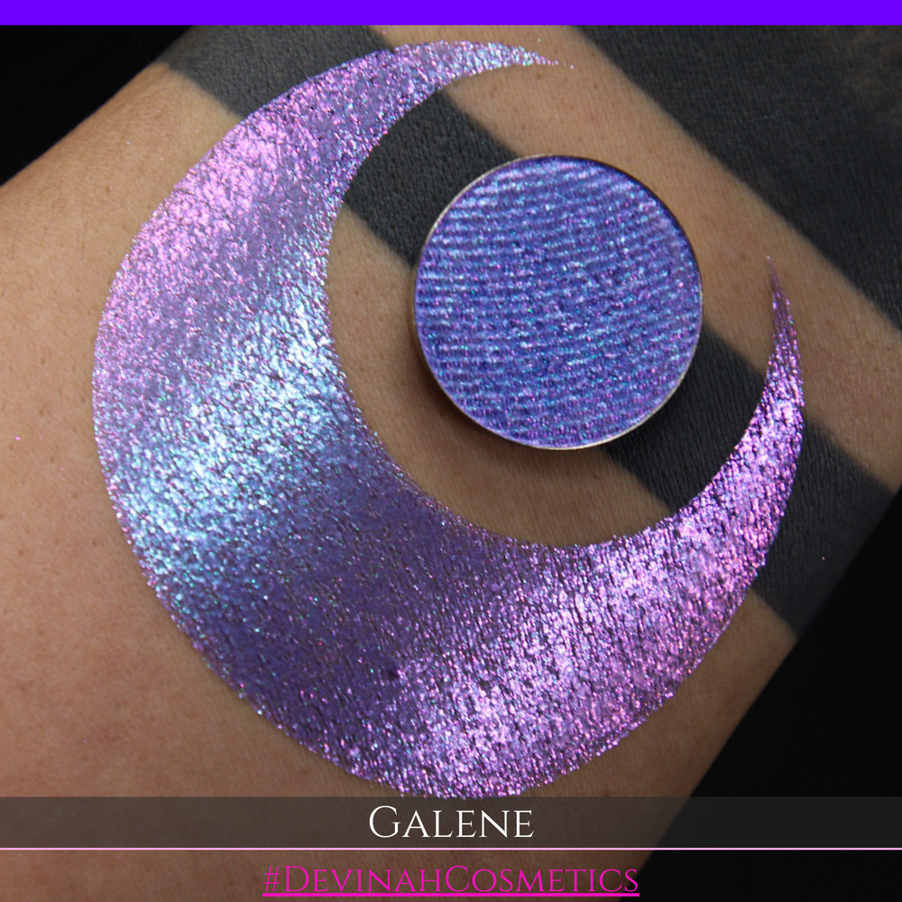 A round eyeshadow pan labeled 'GALENE' made by Devinah Cosmetics, placed over a large crescent moon swatch of the same shimmering shifty eyeshadow on skin. The duochorme multichrome eyeshadow has a shift between colors pink, purple, blue.