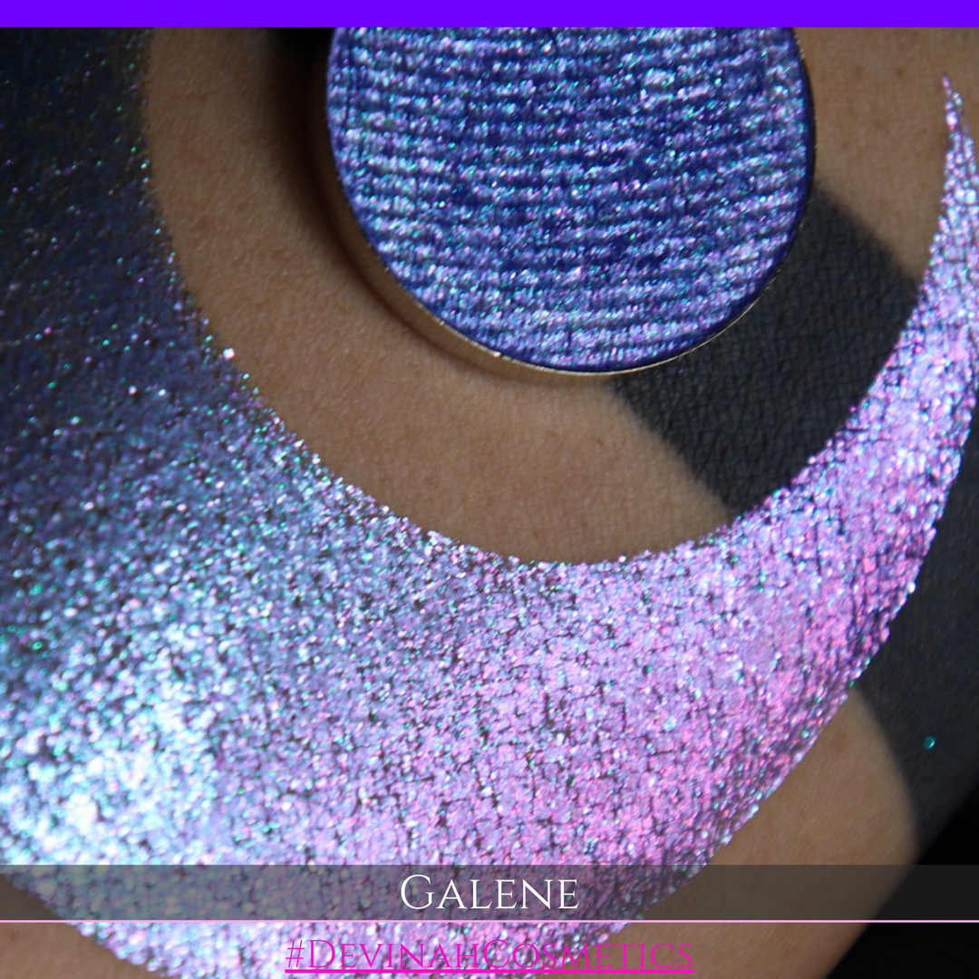 A round eyeshadow pan labeled 'GALENE' made by Devinah Cosmetics, placed over a large crescent moon swatch of the same shimmering shifty eyeshadow on skin. The duochorme multichrome eyeshadow has a shift between colors pink, purple, blue.