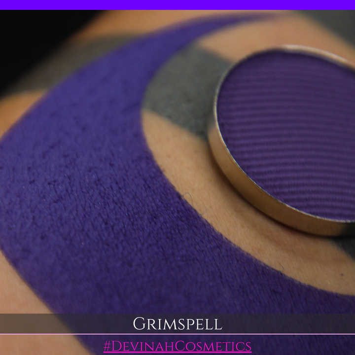 A close-up of a purple matte eyeshadow swatch and the eyeshadow pan. The text 'GRIMSPELL' and '#DEVINAHCosmetics' are displayed at the bottom.