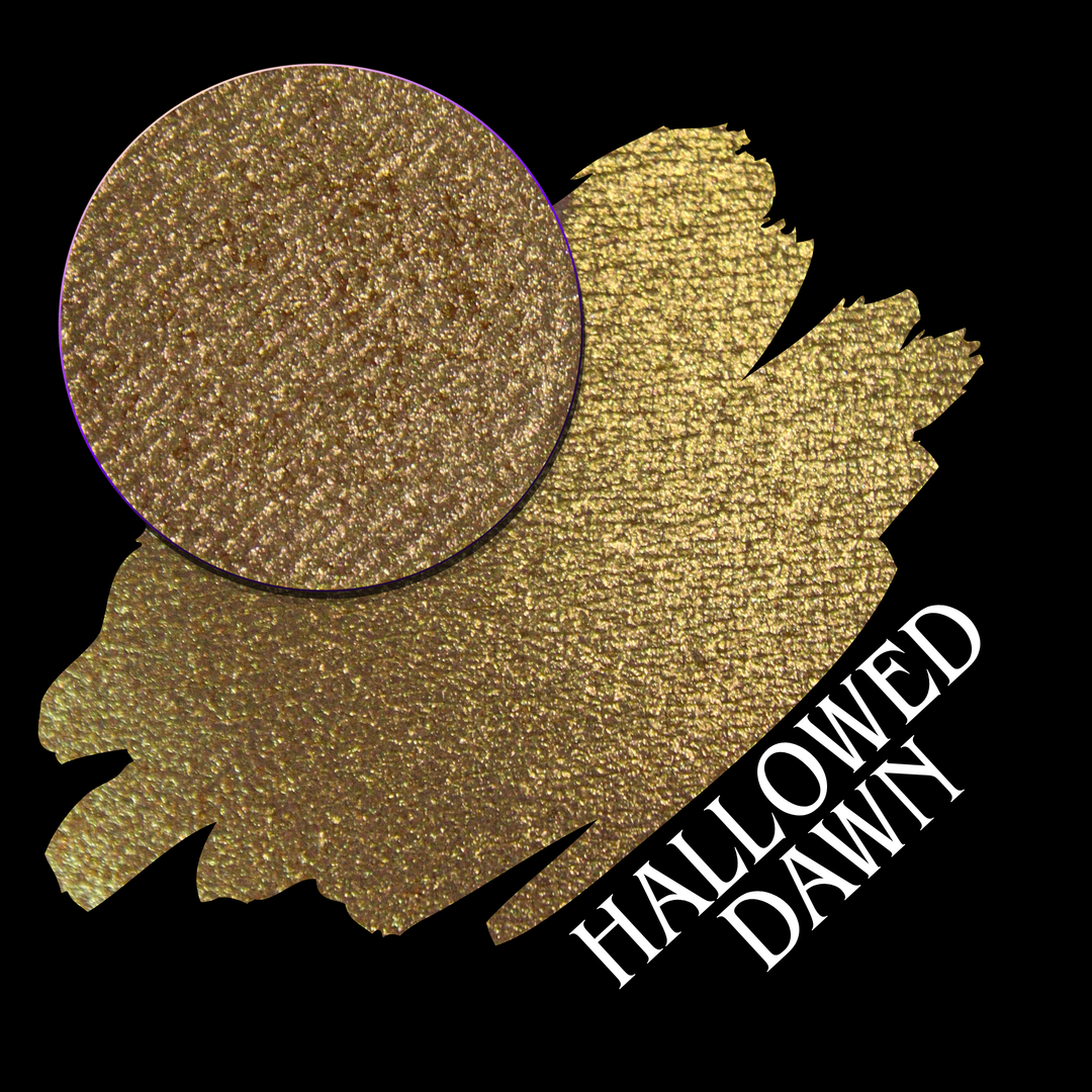 A textured gold eyeshadow swatch with a circular eyeshadow makeup pan on a black background, with the text 'HALLOWED DAWN' in white at the bottom right hand made from Devinah Cosmetics.