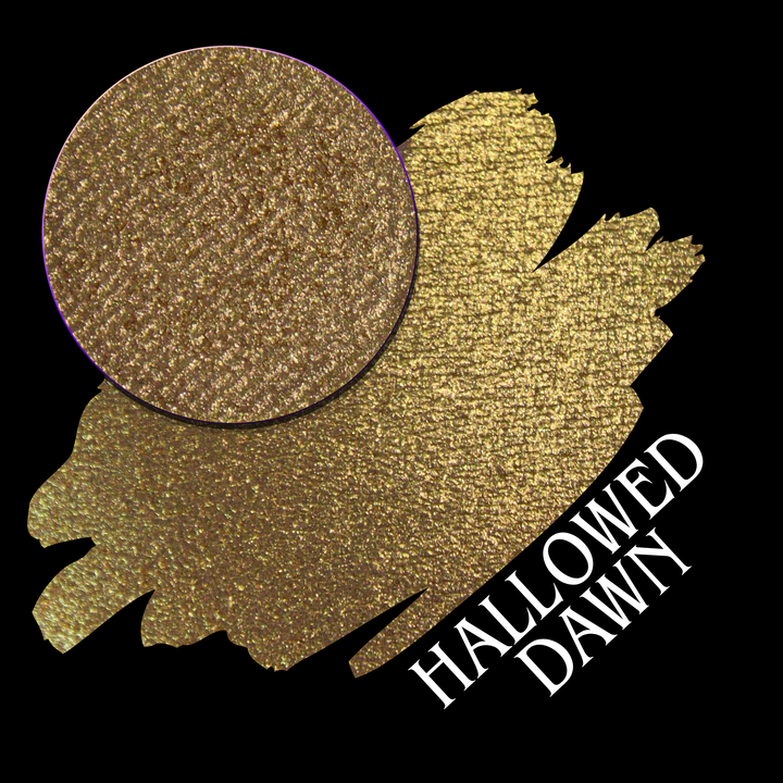 A textured gold eyeshadow swatch with a circular eyeshadow makeup pan on a black background, with the text 'HALLOWED DAWN' in white at the bottom right hand made from Devinah Cosmetics.