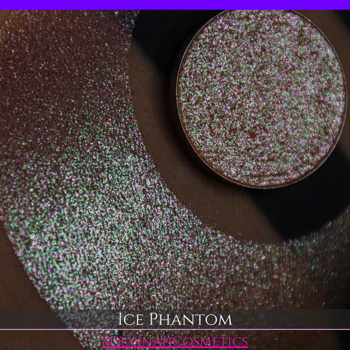 A circular makeup eyeshadow pan of a shimmery rose gold peachy coral eyeshadow labeled 'ICE PHANTOM' by Devinah Cosmetics, shown next to a large swatch on skin.