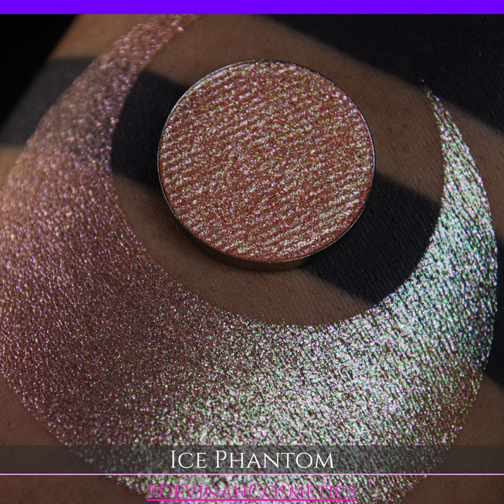 A circular makeup eyeshadow pan of a shimmery rose gold peachy coral eyeshadow labeled 'ICE PHANTOM' by Devinah Cosmetics, shown next to a large swatch on skin.