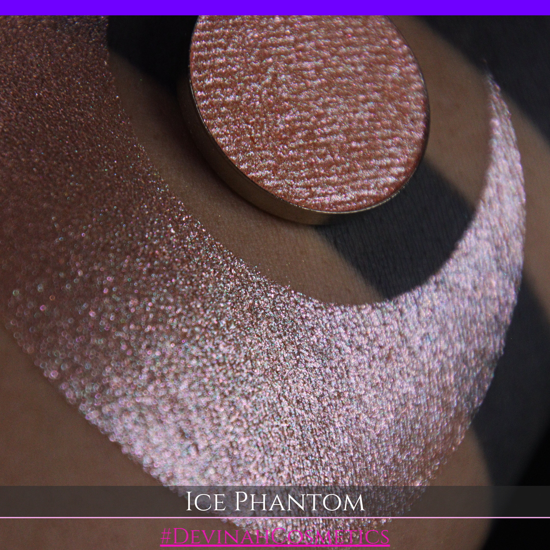 A circular makeup eyeshadow pan of a shimmery rose gold peachy coral eyeshadow labeled 'ICE PHANTOM' by Devinah Cosmetics, shown next to a large swatch on skin.