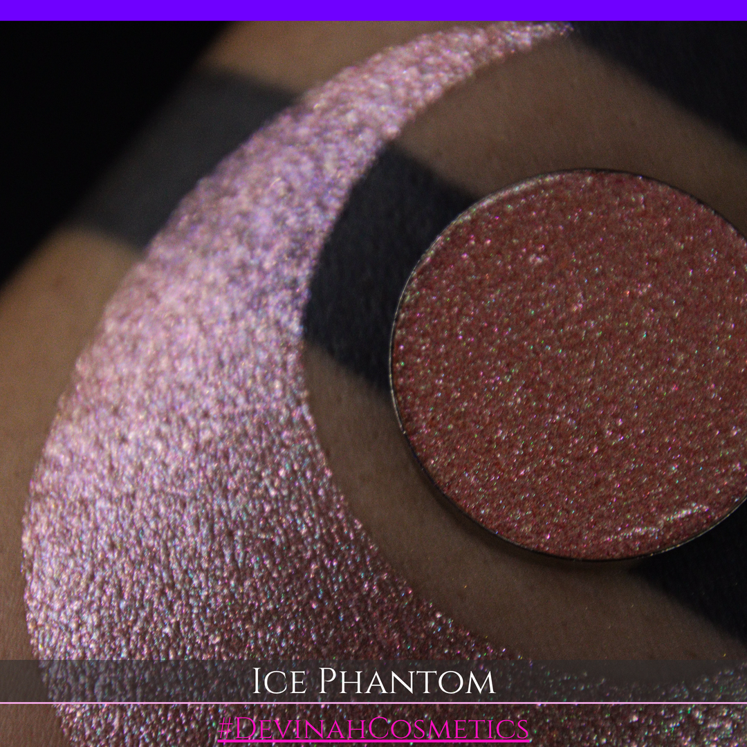 A circular makeup eyeshadow pan of a shimmery rose gold peachy coral eyeshadow labeled 'ICE PHANTOM' by Devinah Cosmetics, shown next to a large swatch on skin.