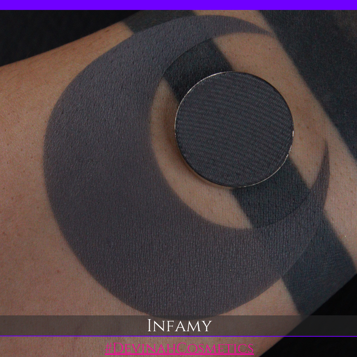 Charcoal gray circular patch on skin with 'Infamy' and 'Devinah Cosmetics' branding.