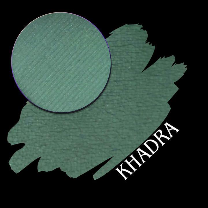 A textured green eyeshadow swatch with a circular makeup eyeshadow pan and the name 'KHADRA' written in white text, set against a solid black background.