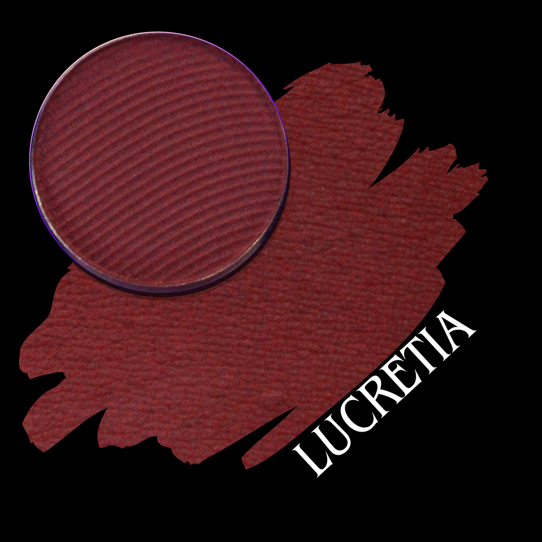 A circular makeup pan of deep berry red pressed powder shown over a matching swatch on a black background, with the name 'LUCRETIA' in white text.
