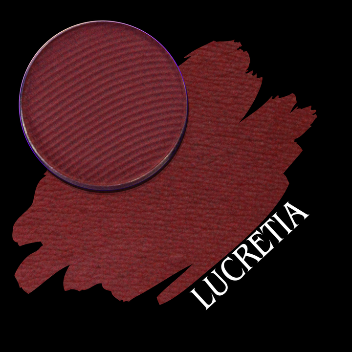 A circular makeup pan of deep berry red pressed powder shown over a matching swatch on a black background, with the name 'LUCRETIA' in white text.