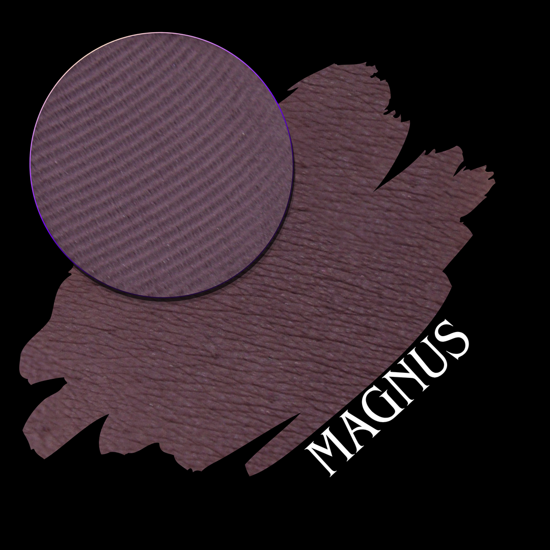 An eyeshadow swatch in a muted plum-purple shade, shown with a circular eyeshadow makeup pan on a black background, labeled MAGNUS in white text.