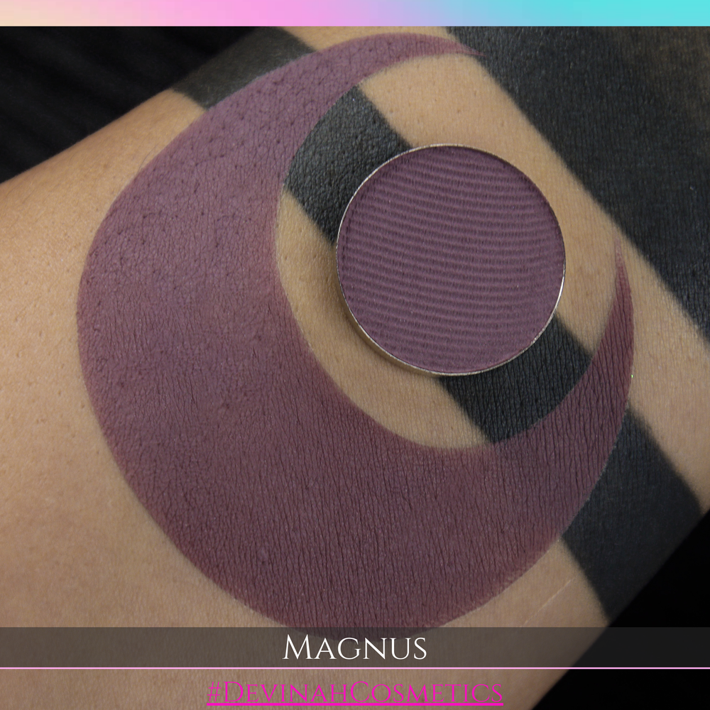 Purple makeup swatch on skin with 'MAGNUS' and 'SOMIUM COSMETICS' branding.