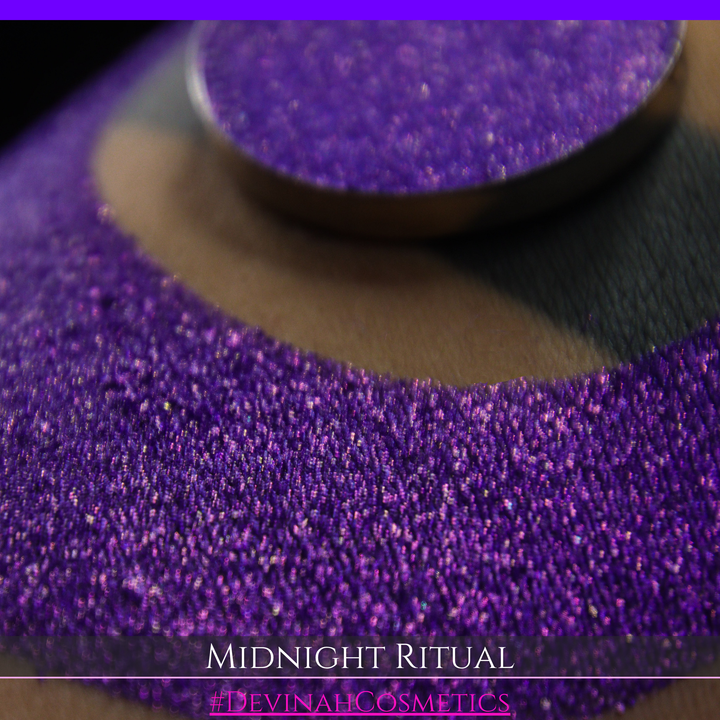A close-up of a large glittery purple makeup swatch and a matching round pan of purple eyeshadow. Text at the bottom reads 'MIDNIGHT RITUAL' and '#DEVINAHCOSMETICS'.