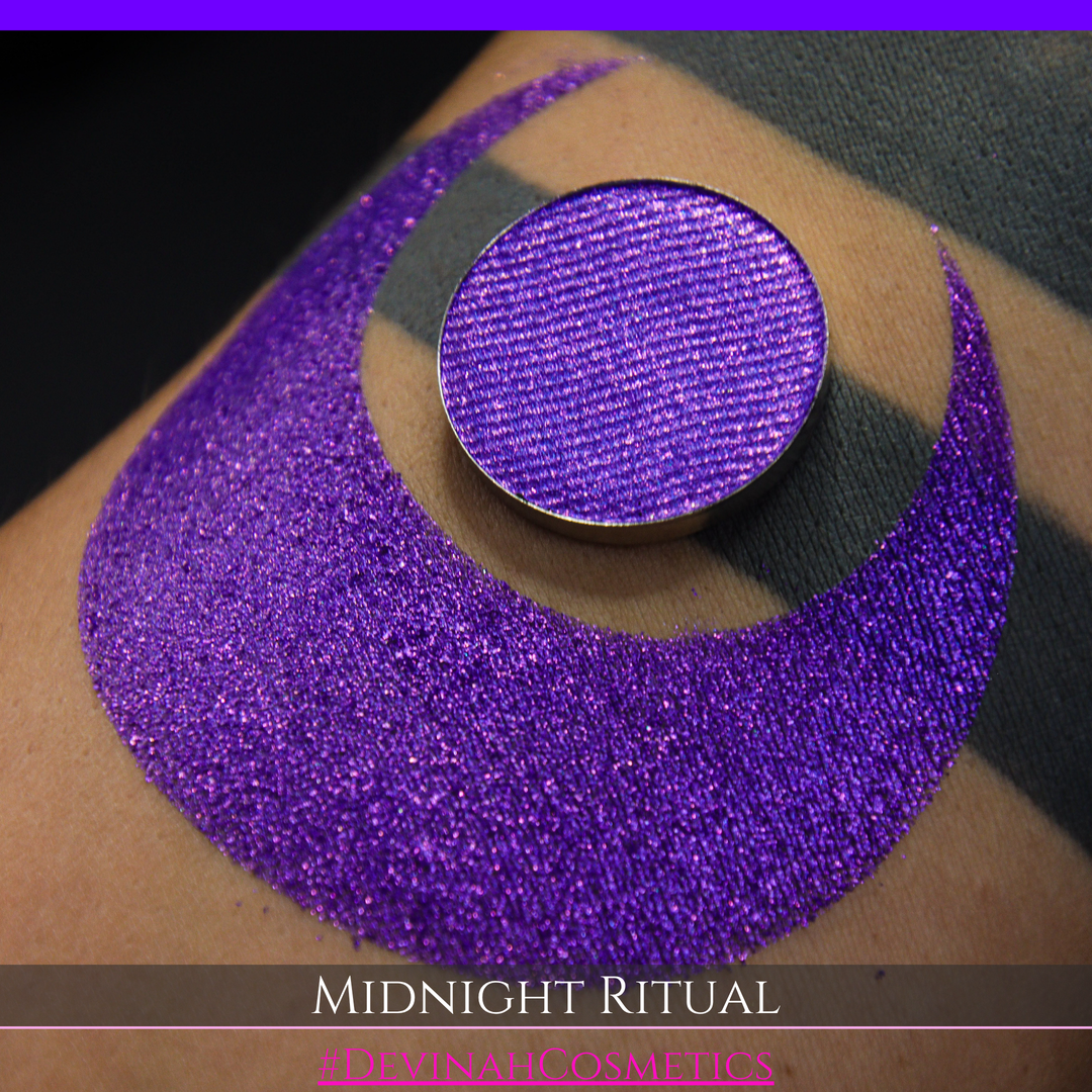 A close-up of a large glittery purple makeup swatch and a matching round pan of purple eyeshadow. Text at the bottom reads 'MIDNIGHT RITUAL' and '#DEVINAHCOSMETICS'.