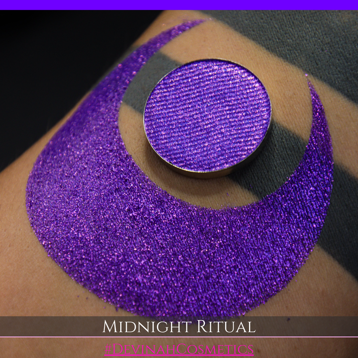A close-up of a large glittery purple makeup swatch and a matching round pan of purple eyeshadow. Text at the bottom reads 'MIDNIGHT RITUAL' and '#DEVINAHCOSMETICS'.