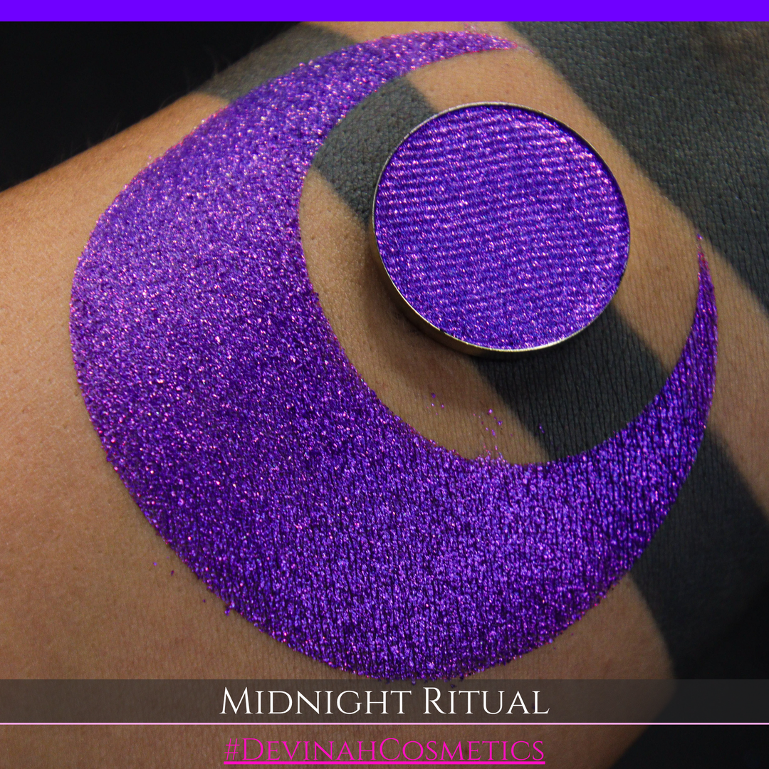 A close-up of a large glittery purple makeup swatch and a matching round pan of purple eyeshadow. Text at the bottom reads 'MIDNIGHT RITUAL' and '#DEVINAHCOSMETICS'.