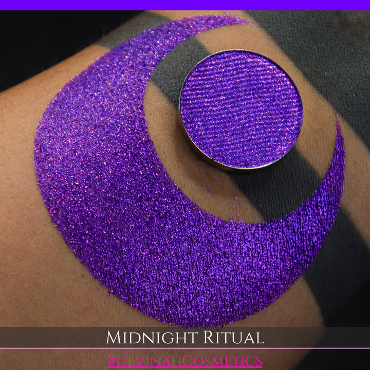 A close-up of a large glittery purple makeup swatch and a matching round pan of purple eyeshadow. Text at the bottom reads 'MIDNIGHT RITUAL' and '#DEVINAHCOSMETICS'.