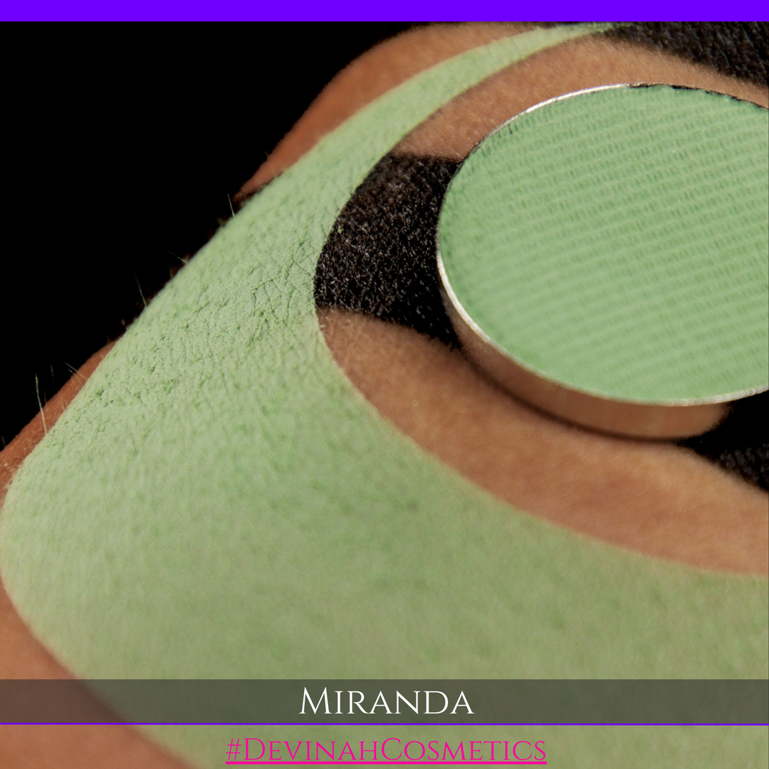 A close-up of a person's eyebrow area showing a light green eyebrow pencil or makeup pan applied, with a green eyebrow patch or stencil underneath. The text overlay at the bottom reads 'MIRANDA' and '#DEVINAHCOSMETICS'.