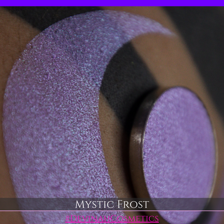 A textured eyeshadow swatch labeled 'MYSTIC FROST' with a purple-to-teal gradient, showing a circular eyeshadow makeup pan on a black background hand made by Devinah Cosmetics.