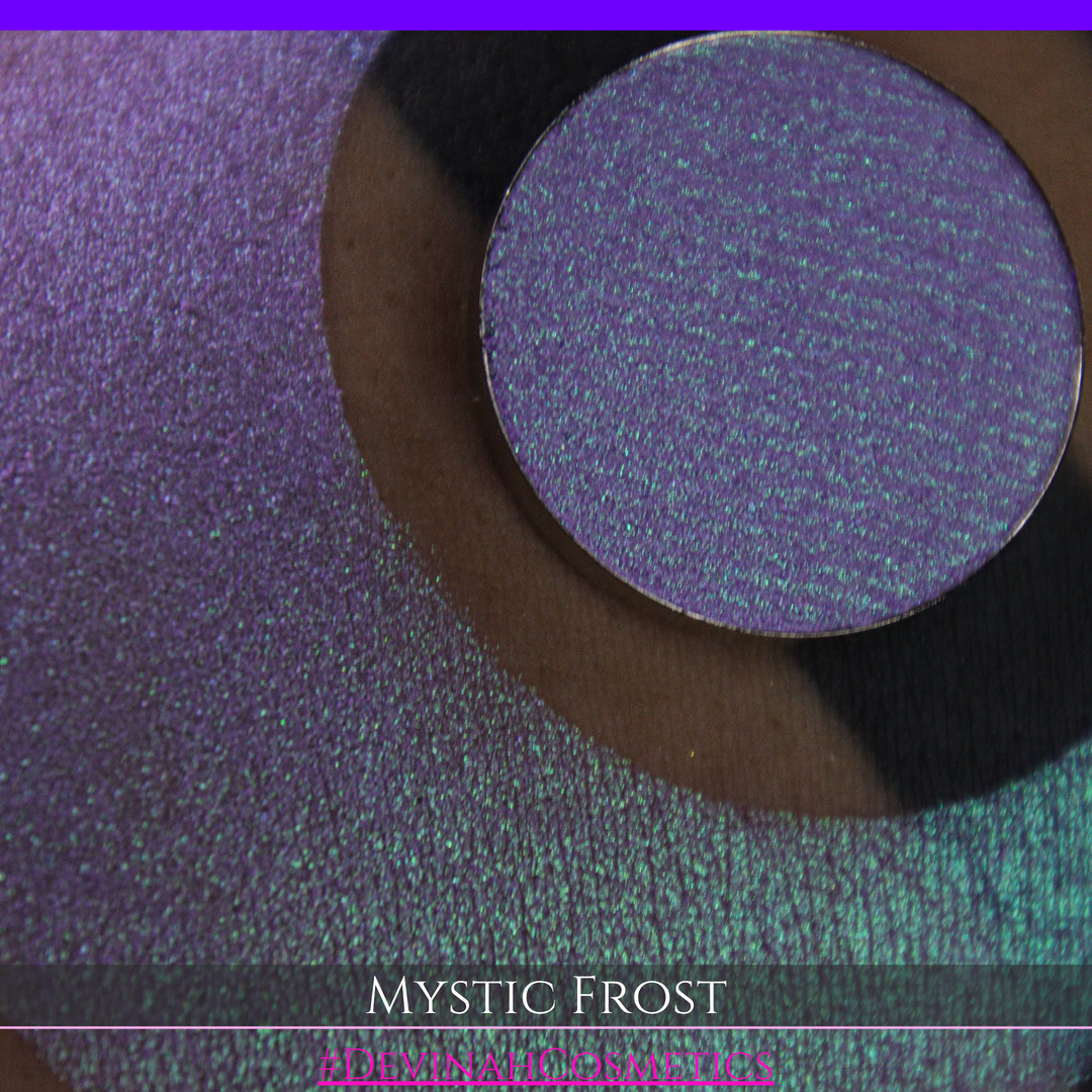 A textured eyeshadow swatch labeled 'MYSTIC FROST' with a purple-to-teal gradient, showing a circular eyeshadow makeup pan on a black background hand made by Devinah Cosmetics.