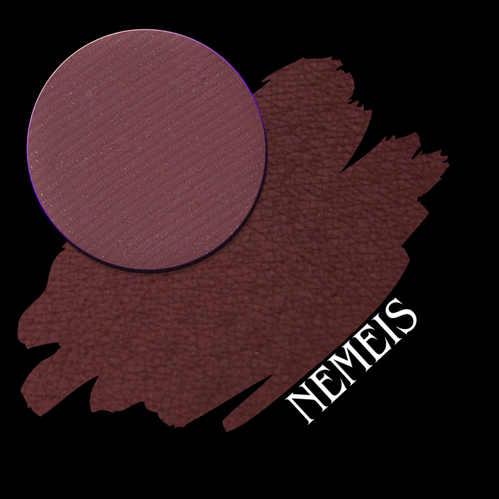 A makeup swatch image showing a circular makeup eyeshadow pan of a deep berry-brown eyeshadow pigment, placed over a large swatch of the same shade on a black background. The word 'NEMESIS' appears in white text over the lower right smear.