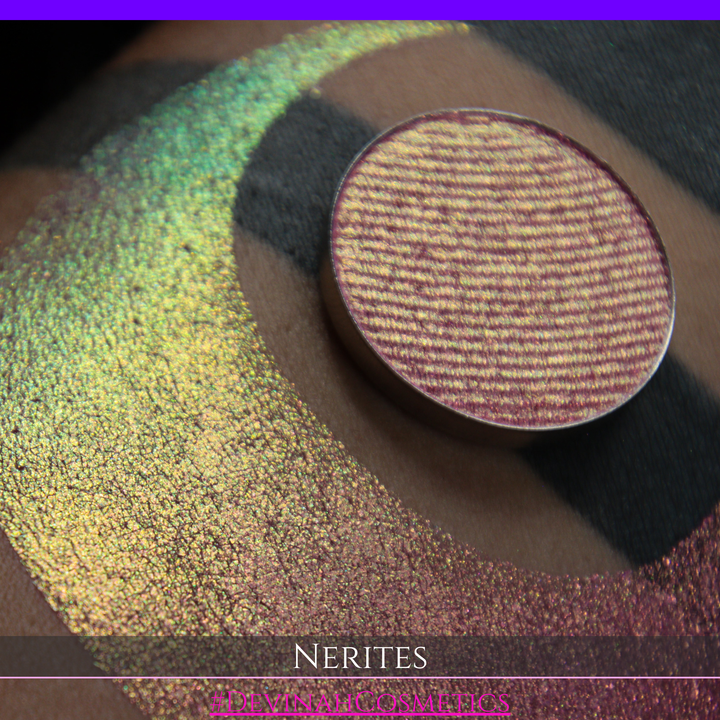 A round eyeshadow pan labeled 'NERITES' made by Devinah Cosmetics, placed over a large crescent moon swatch of the same shimmering multichrome eyeshadow on skin. The eyeshadow has a shimmer sparkle finish shifting between colors pink, yellow, gold, green.