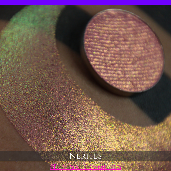 A round eyeshadow pan labeled 'NERITES' made by Devinah Cosmetics, placed over a large crescent moon swatch of the same shimmering multichrome eyeshadow on skin. The eyeshadow has a shimmer sparkle finish shifting between colors pink, yellow, gold, green.