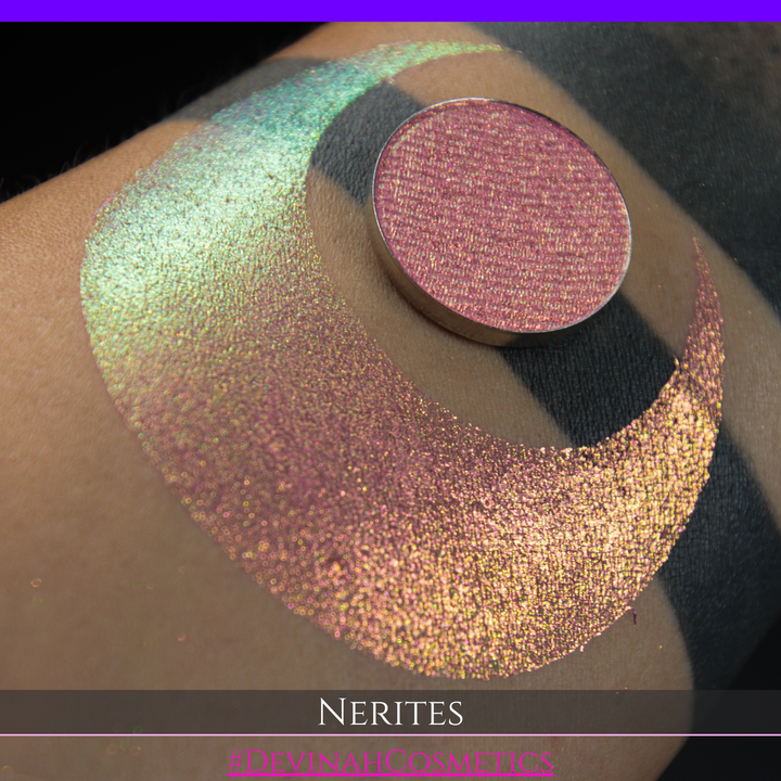 A round eyeshadow pan labeled 'NERITES' made by Devinah Cosmetics, placed over a large crescent moon swatch of the same shimmering multichrome eyeshadow on skin. The eyeshadow has a shimmer sparkle finish shifting between colors pink, yellow, gold, green.