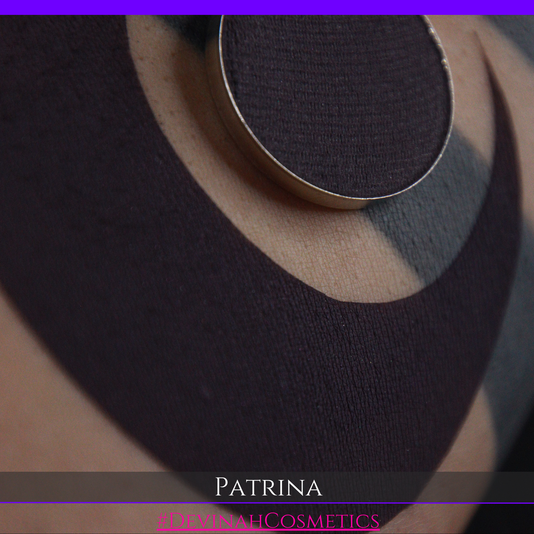 A close-up of a blackened plum matte eyeshadow pressed powder pan with a swatch. The name 'PATRINA' and the text '#DEVINAHCOSMETICS' are displayed at the bottom.