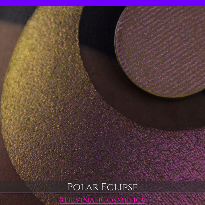 A close-up of a swatch and a circular  shimmering eyeshadow pan in a yellow-to-iridescent pink tone. Text at the bottom reads 'POLAR ECLIPSE' and '#DEVINAH Cosmetics'.