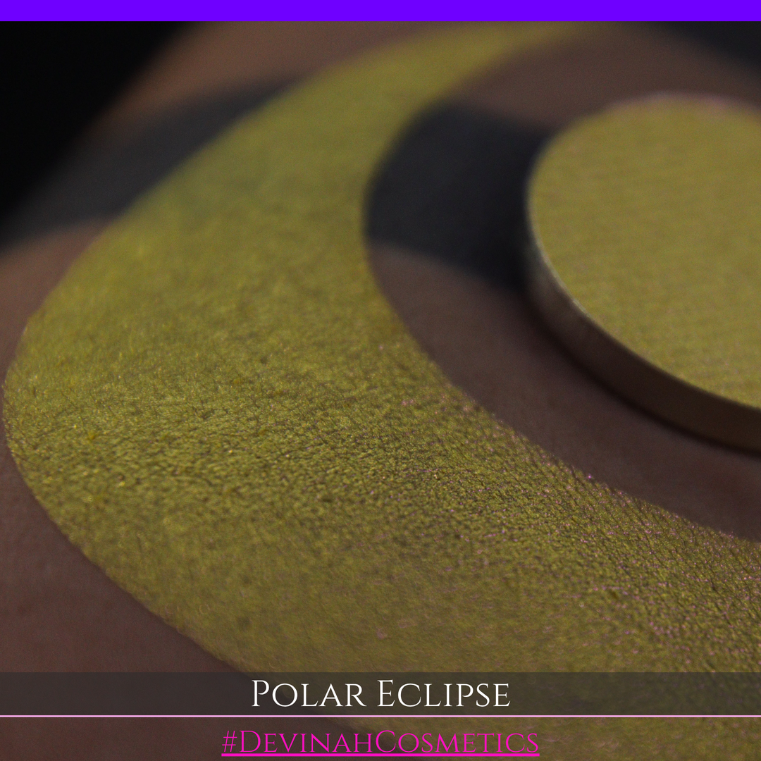 A close-up of a swatch and a circular  shimmering eyeshadow pan in a yellow-to-iridescent pink tone. Text at the bottom reads 'POLAR ECLIPSE' and '#DEVINAH Cosmetics'.