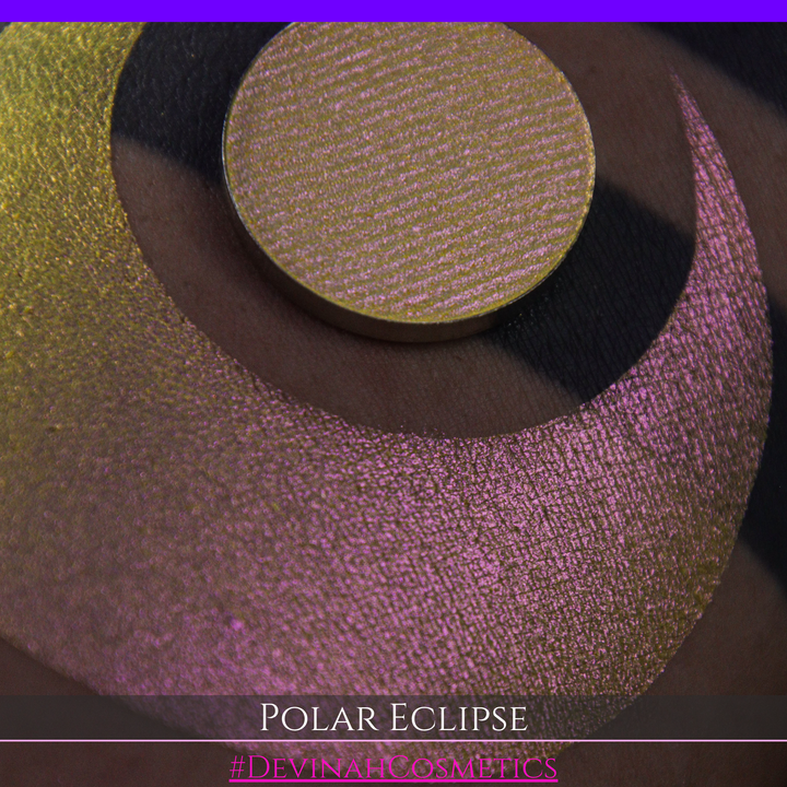 A close-up of a swatch and a circular  shimmering eyeshadow pan in a yellow-to-iridescent pink tone. Text at the bottom reads 'POLAR ECLIPSE' and '#DEVINAH Cosmetics'.