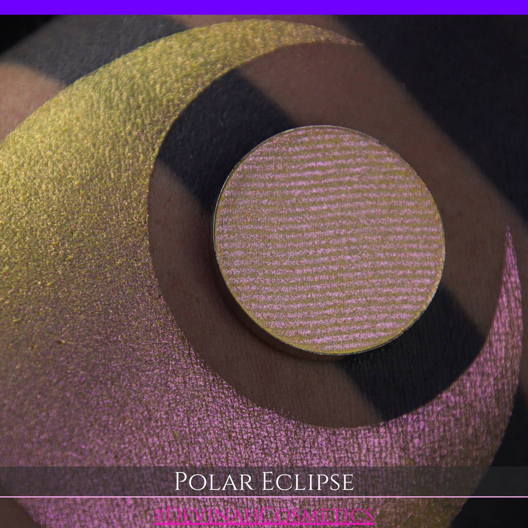 A close-up of a swatch and a circular  shimmering eyeshadow pan in a yellow-to-iridescent pink tone. Text at the bottom reads 'POLAR ECLIPSE' and '#DEVINAH Cosmetics'.