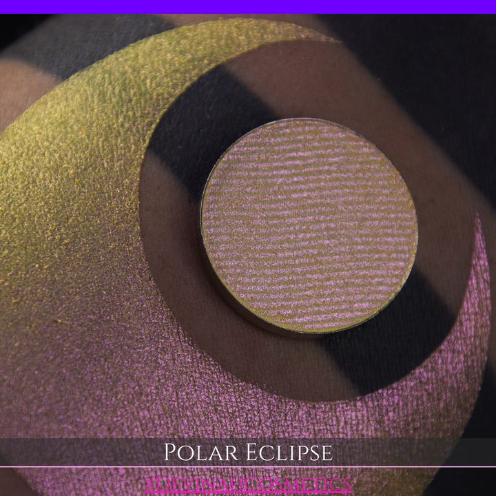 A close-up of a swatch and a circular  shimmering eyeshadow pan in a yellow-to-iridescent pink tone. Text at the bottom reads 'POLAR ECLIPSE' and '#DEVINAH Cosmetics'.