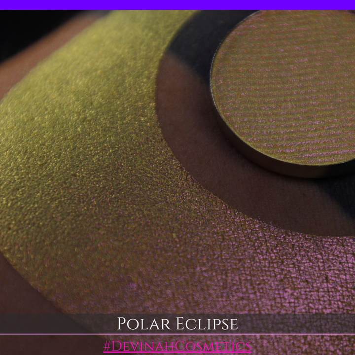 A close-up of a swatch and a circular  shimmering eyeshadow pan in a yellow-to-iridescent pink tone. Text at the bottom reads 'POLAR ECLIPSE' and '#DEVINAH Cosmetics'.