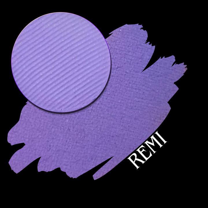A circular eyeshadow makeup pan in a lavender-purple shade is shown over a matching purple swatch on a black background, with the text 'REMI' in white at the lower right.