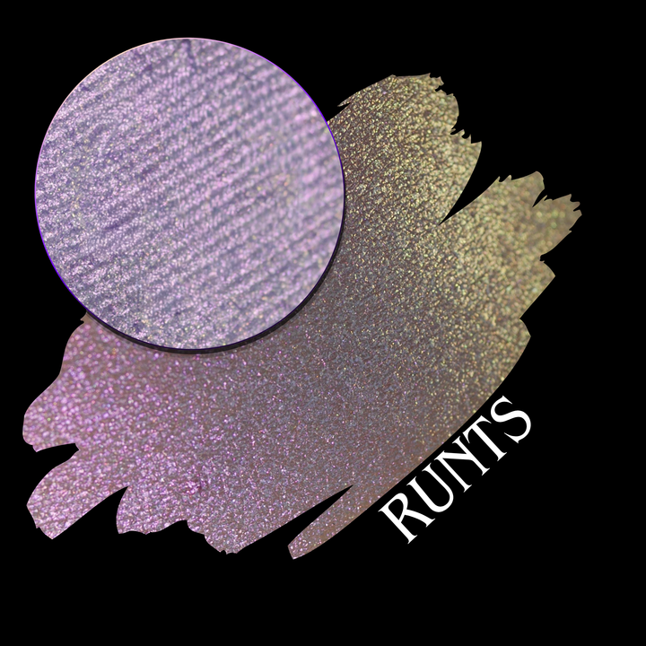 A round eyeshadow pan labeled 'RUNTS' made by Devinah Cosmetics, placed over a large crescent moon swatch of the same shimmering shifty eyeshadow on skin. The eyeshadow has a duochrome multichrome shift between colors purple pink and yellow