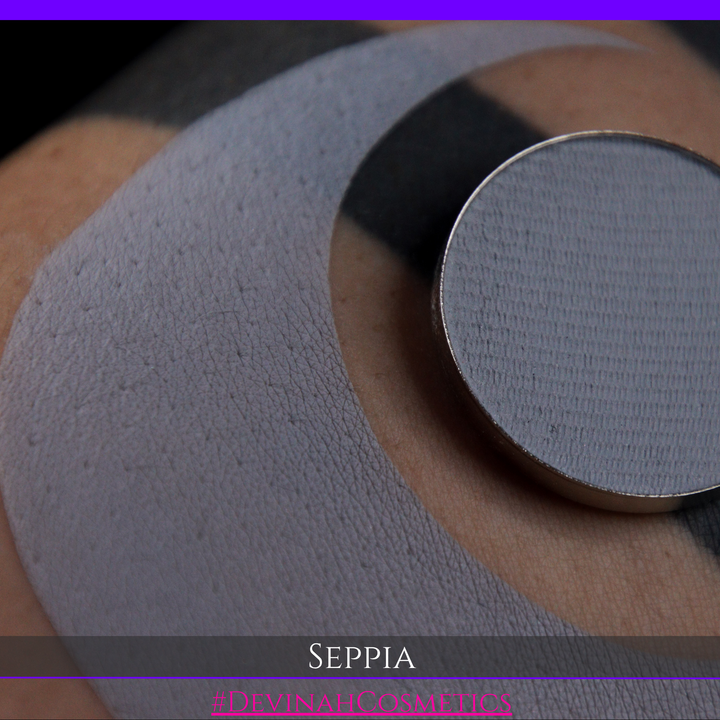 A close-up of a circular makeup eyeshadow matte pigment pan of 'Seppia' eyeshadow with a swatch of the matte eyeshadow. The brand name 'DEVINAH COSMETICS' is visible at the bottom