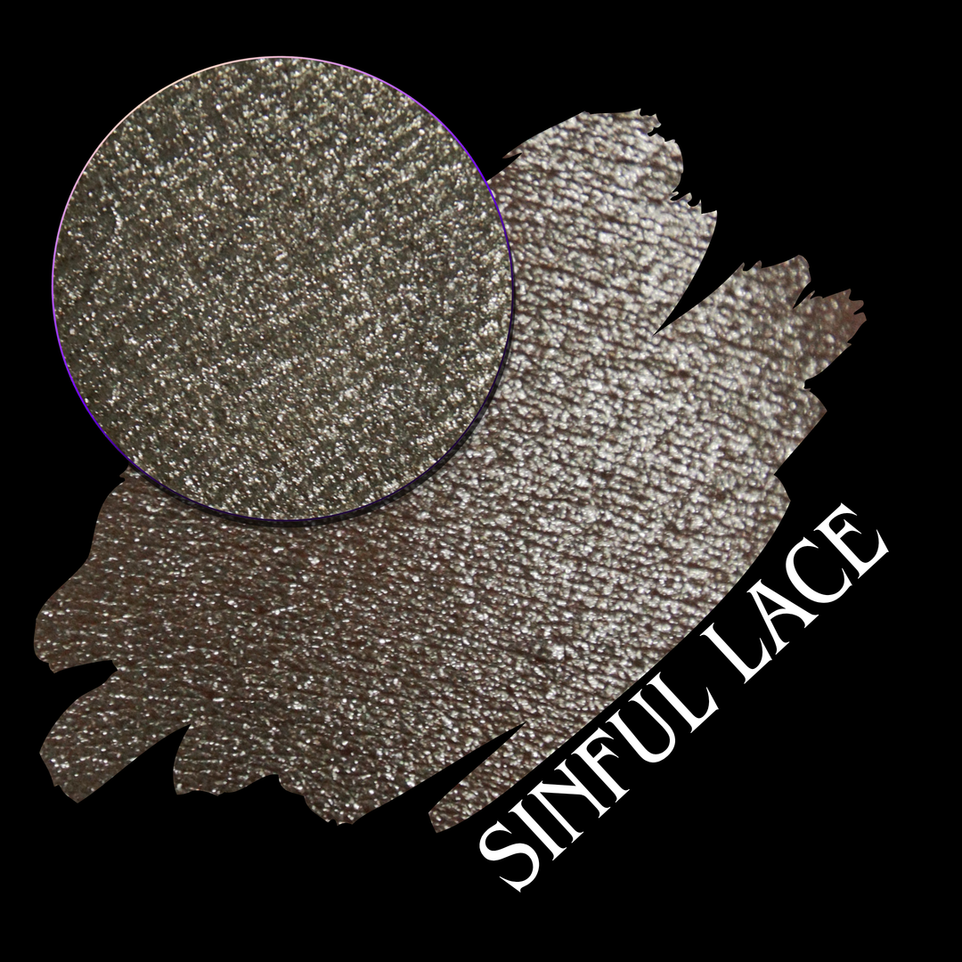 A round eyeshadow pan labeled 'SINFUL LACE' made by Devinah Cosmetics, placed over a large crescent moon swatch of the same shimmering shifty eyeshadow on skin. The eyeshadow has colors of sparkly beige creme tan shimmer.