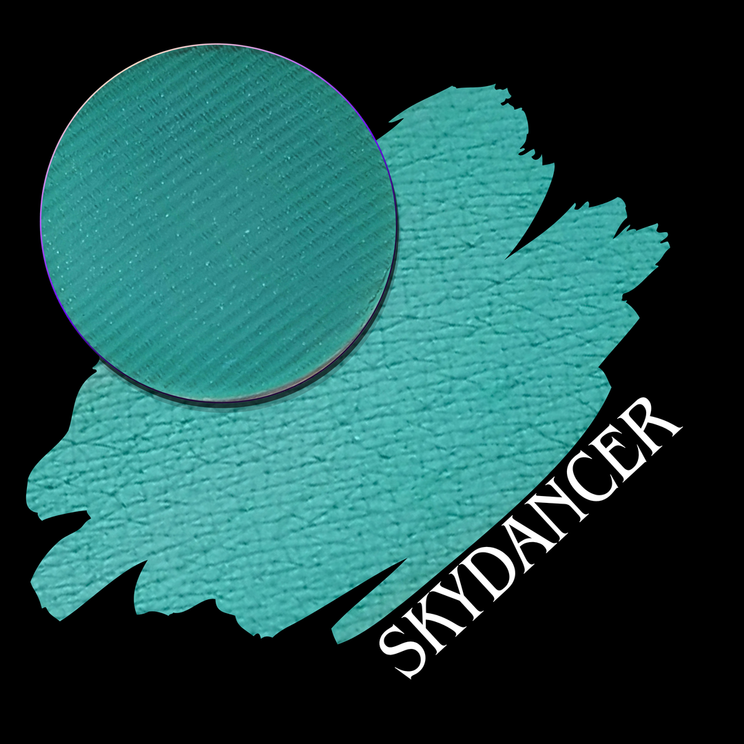 A teal eyeshadow color swatch shown with a circular makeup single eyeshadow pan over on a black background, with the text 'SKYDANCER' in white at the bottom right.