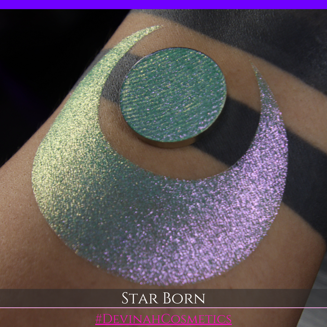 A close-up of a person's skin with a large iridescent crescent moon makeup swatch and a matching circular eyeshadow pan in the center. The text 'STAR BORN' and 'Devinah Cosmetics' appears at the bottom.